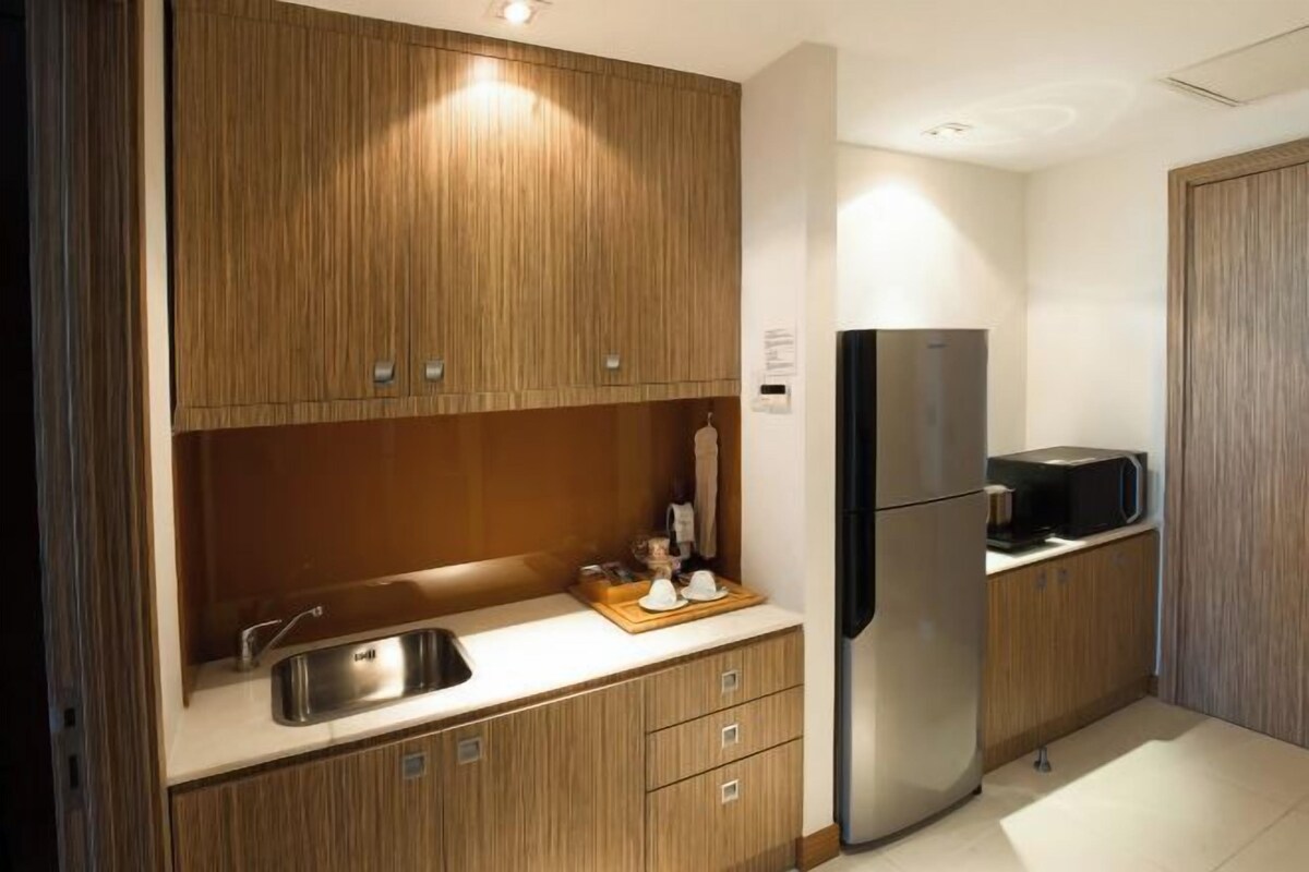 Una cocina moderna con armarios de madera, un refrigerador de acero inoxidable y un microondas.