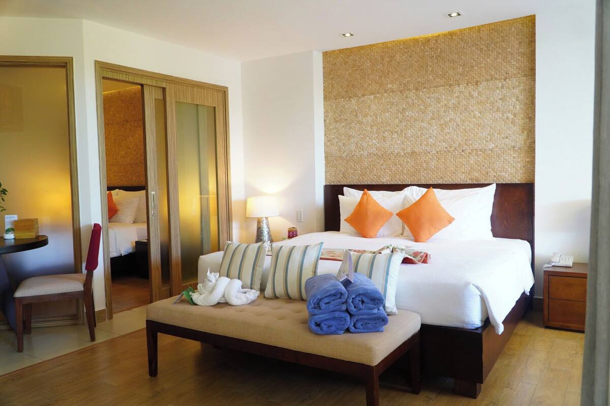 A hotel room with a bed, a chair, a table, and a nightstand.