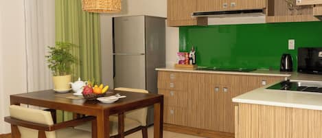 Una cocina moderna con armarios de madera, una mesa de comedor con sillas, una lámpara colgante y un salpicadero verde.