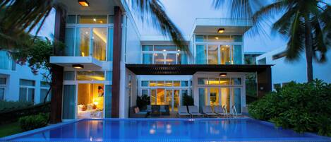 A modern two-story building with a swimming pool in front.