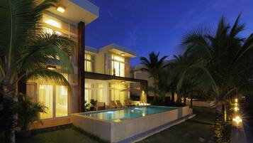 Una casa moderna con piscina, ventanas amplias y palmeras.