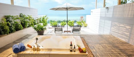 Un espacio de spa con jacuzzi, asientos y vistas al océano.