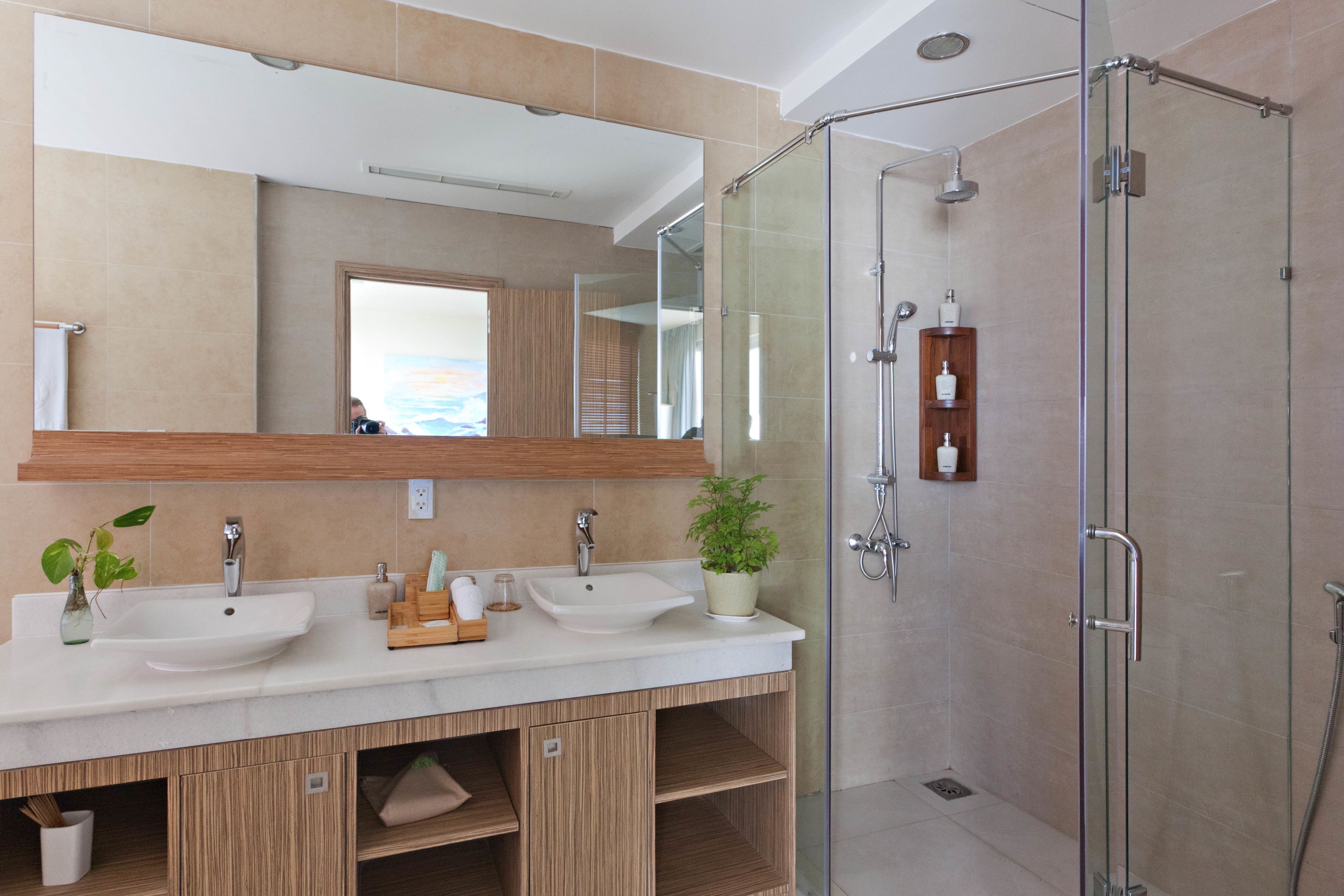 Un baño moderno con dos lavamanos, cabina de ducha con mampara de vidrio y un espejo grande.