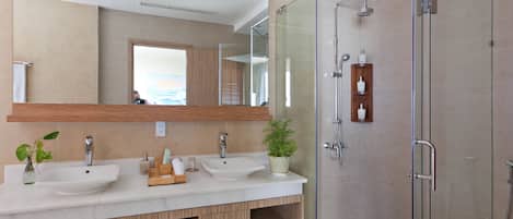Un baño moderno con dos lavamanos, cabina de ducha con mampara de vidrio y un espejo grande.
