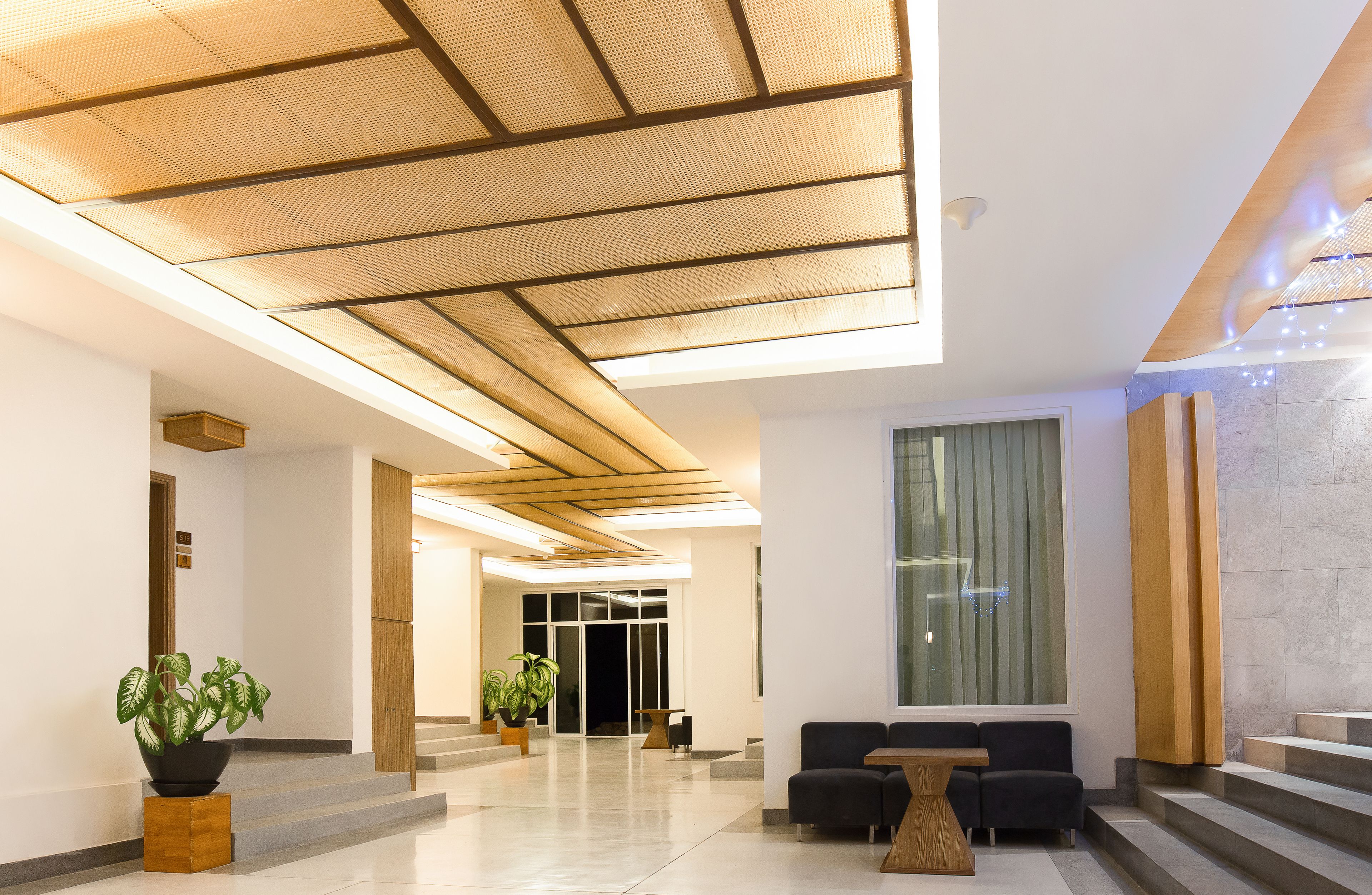 Un vestíbulo moderno con techo alto, ventanas amplias y un mostrador de recepción.