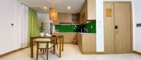 Una cocina compacta con comedor, que cuenta con un refrigerador moderno, microondas y salpicadero verde.