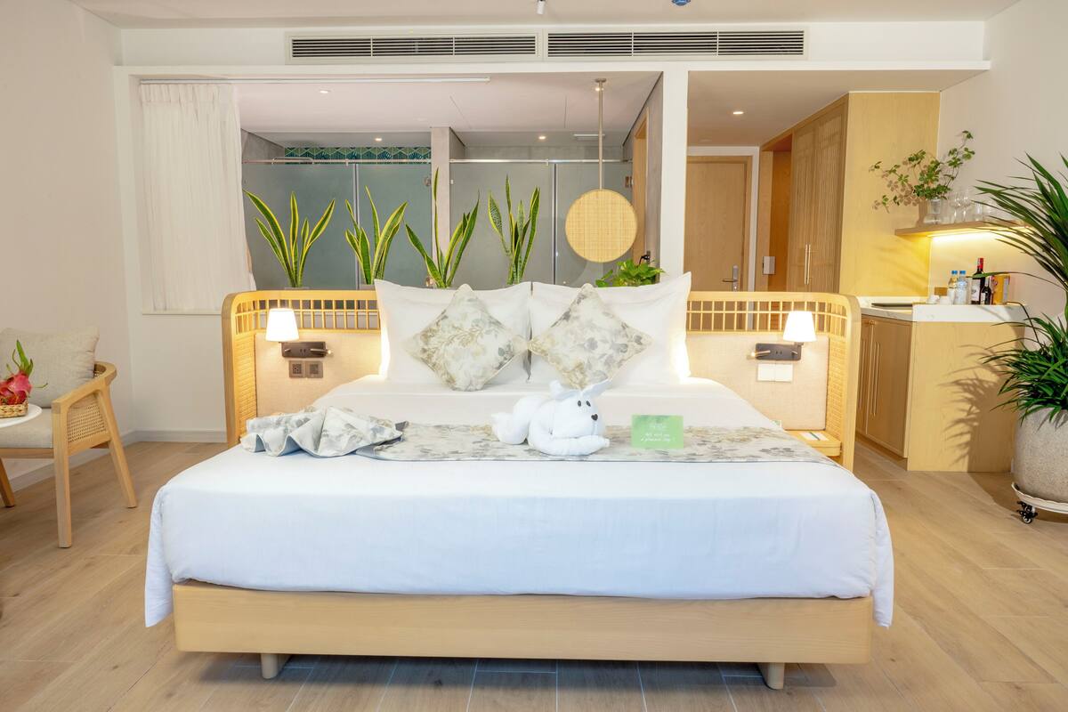A hotel room with a large bed, bedside tables, a chair, and a desk.