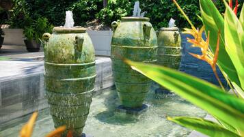 A series of large, green, weathered water fountains in a garden setting.