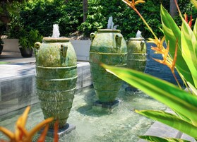 Varias fuentes de agua grandes, verdes y desgastadas por el clima, ubicadas en un jardín.