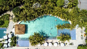 An aerial view of a resort with a large swimming pool surrounded by palm trees and lounge chairs. - The Cliff Resort & Residences (Phu Thuy)