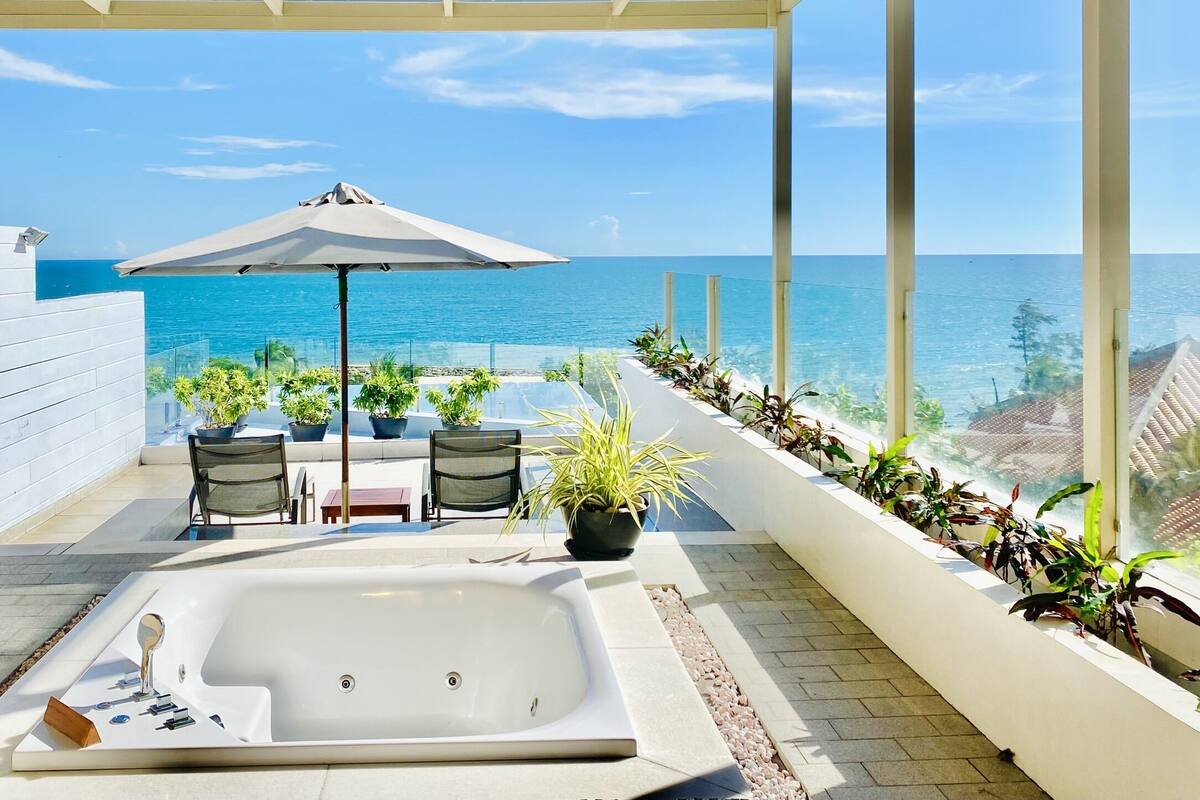 A rooftop terrace with a hot tub, seating area, and potted plants.
