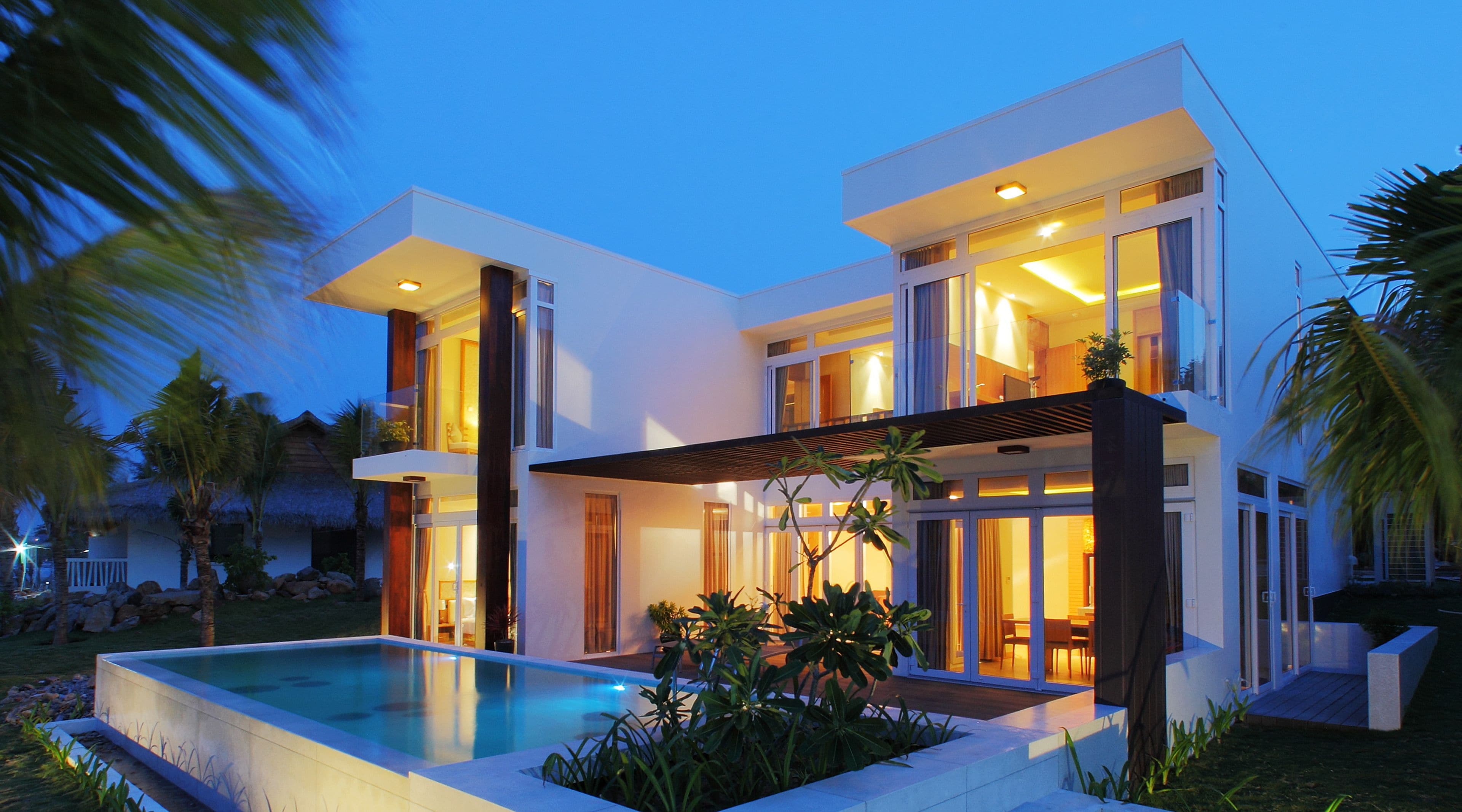A modern two-story house with a swimming pool, large windows, and a covered patio area.