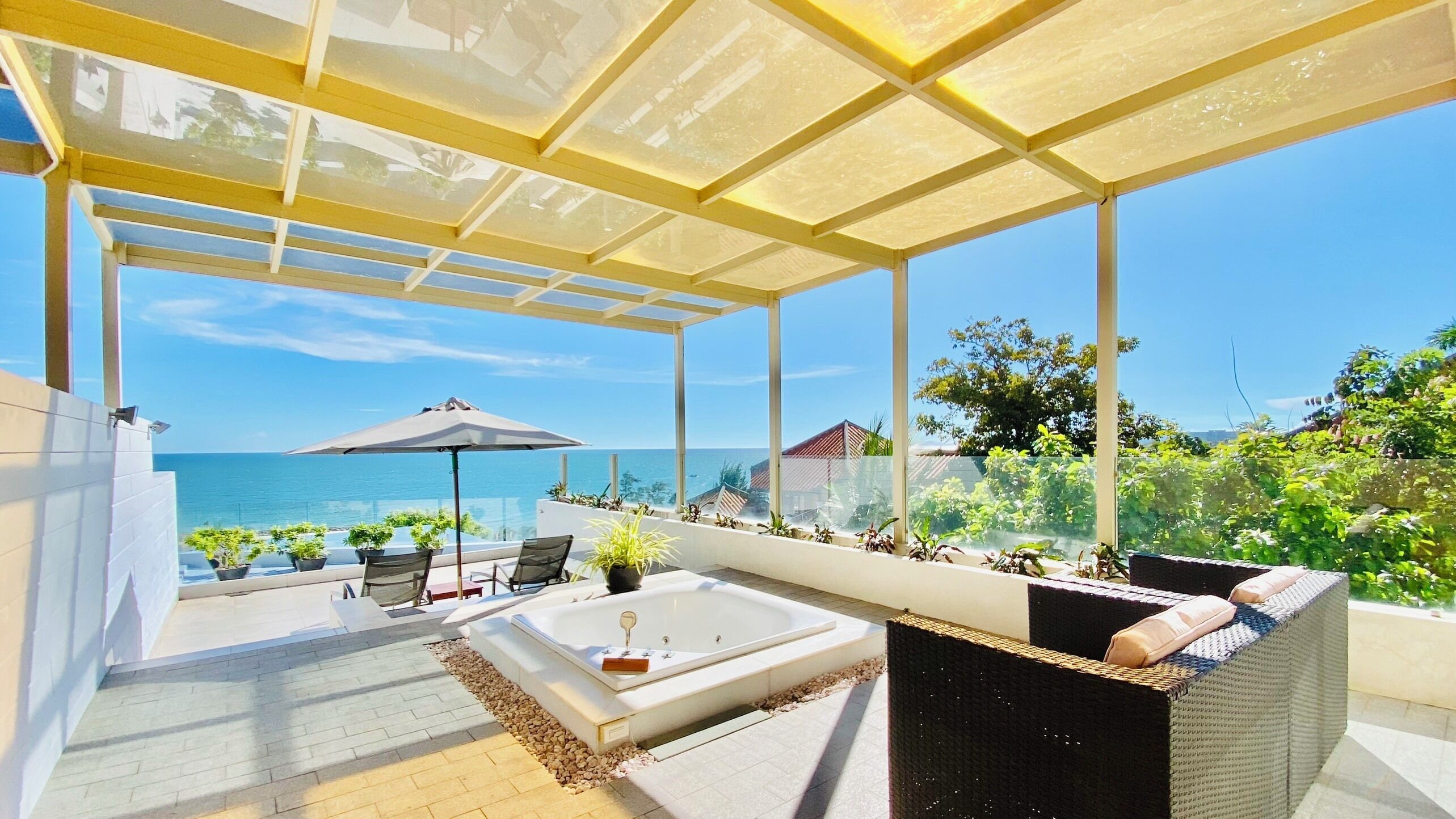 A covered outdoor area with a pool, seating, and a view of the sea.