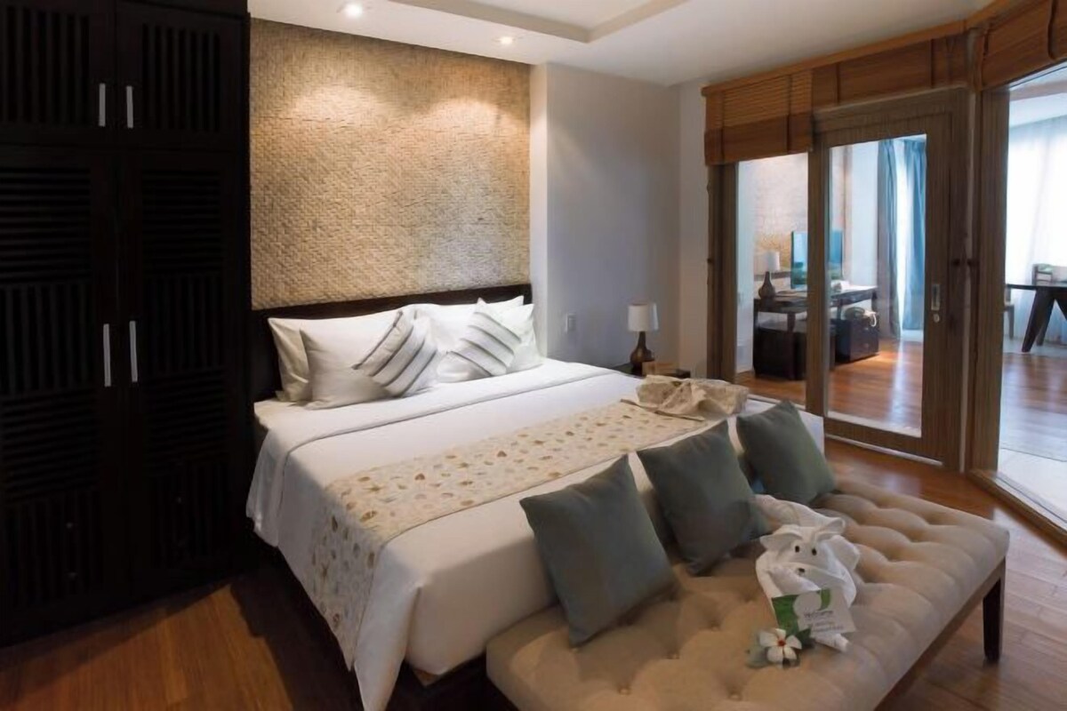 Una habitación de hotel con una cama grande, un sofá y vistas a través de un ventanal.