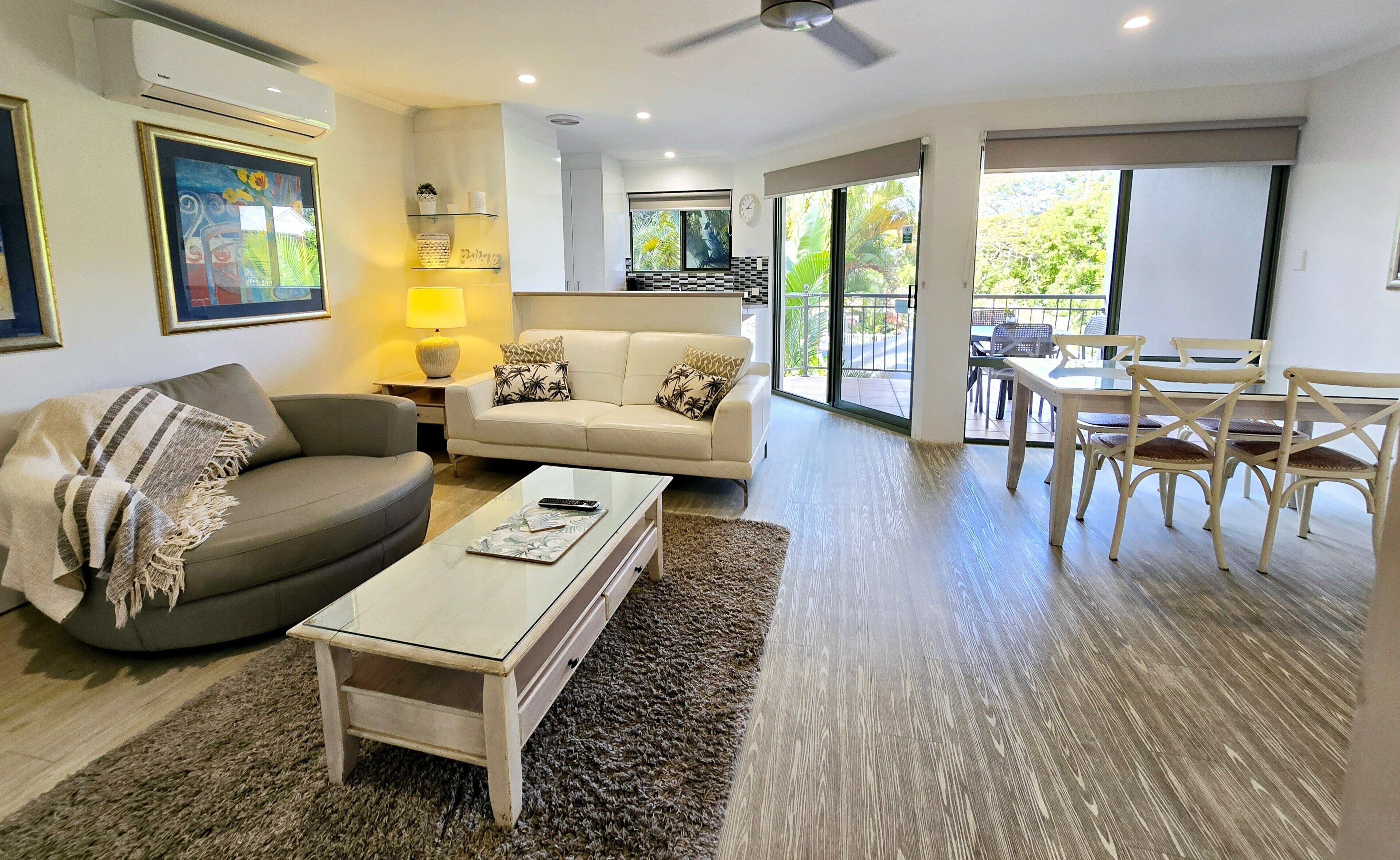 A living room with a sofa, coffee table, and a dining area with chairs.
