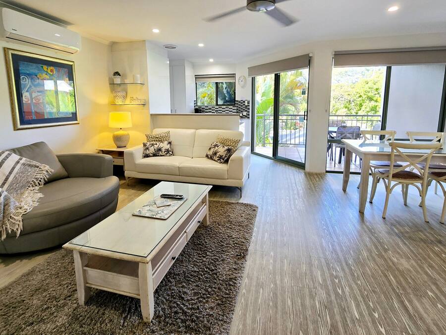 A living room with a sofa, coffee table, and a dining area with chairs.