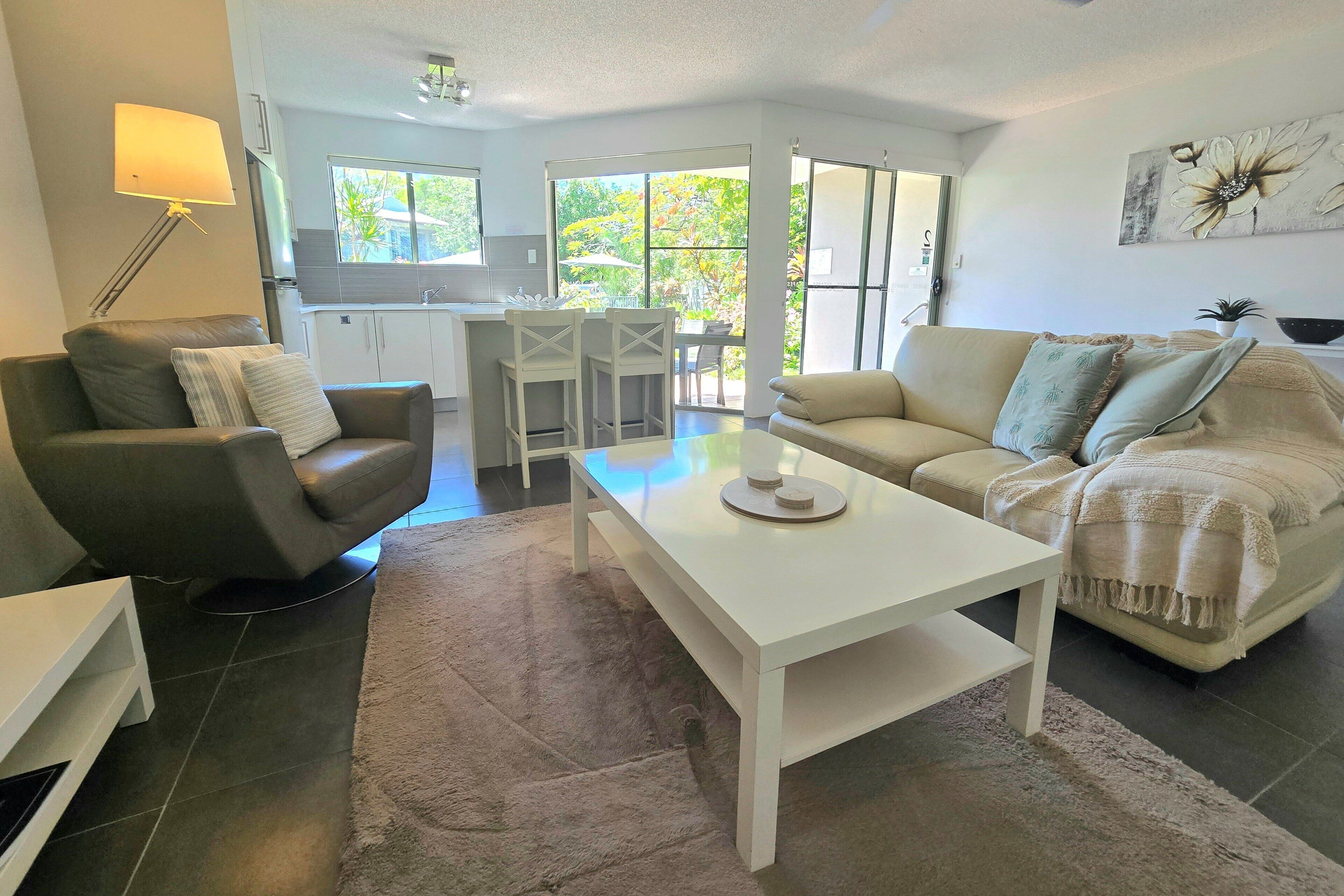 A modern living room with a sofa, a coffee table, and a dining area with chairs.