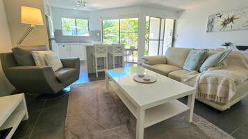 A modern living room with a sofa, a coffee table, and a dining area with chairs.