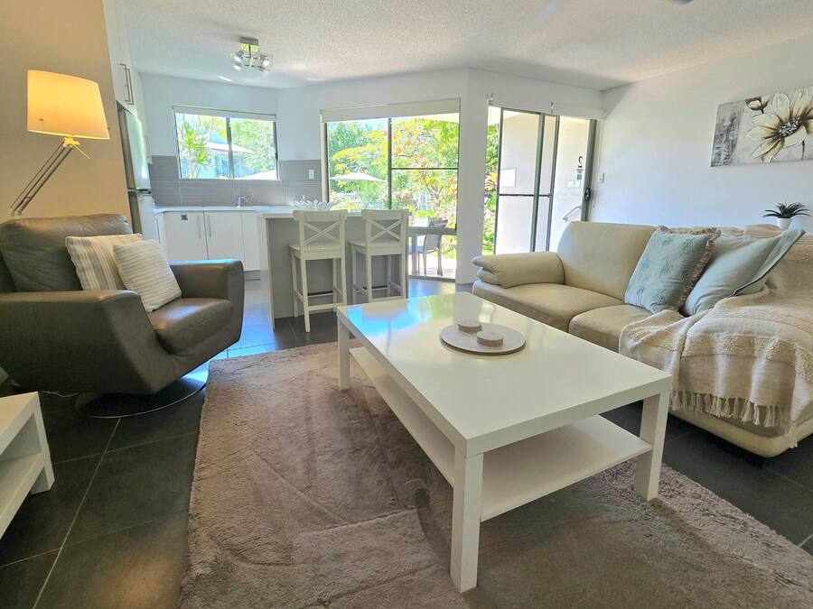 A modern living room with a sofa, a coffee table, and a dining area with chairs.