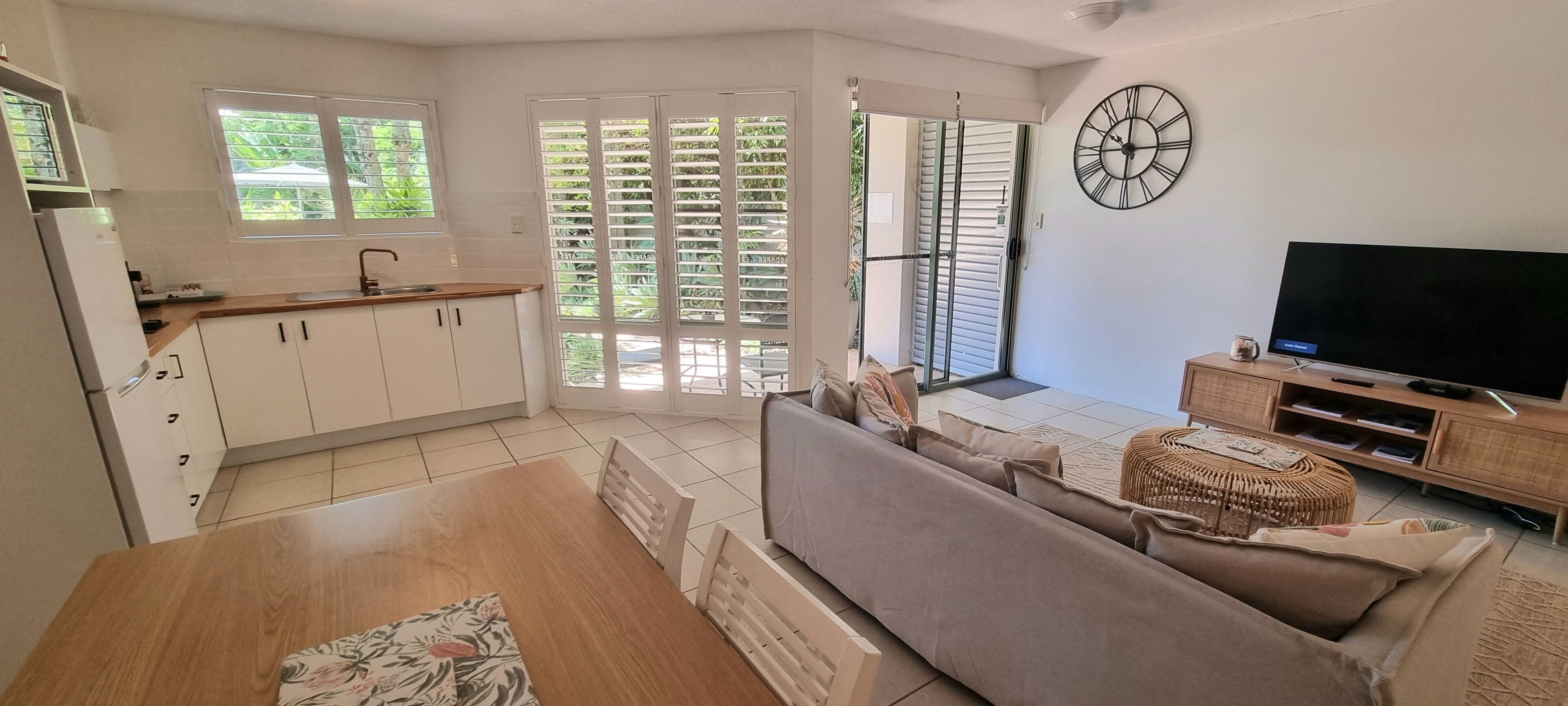 Una sala de estar moderna con un sofá, televisor y comedor con mesa y sillas.