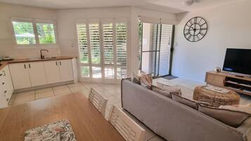 Una sala de estar moderna con un sofá, televisor y comedor con mesa y sillas.