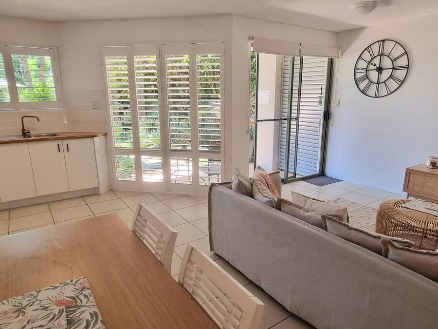 A modern living room with a sofa, TV, and a dining area with a table and chairs.
