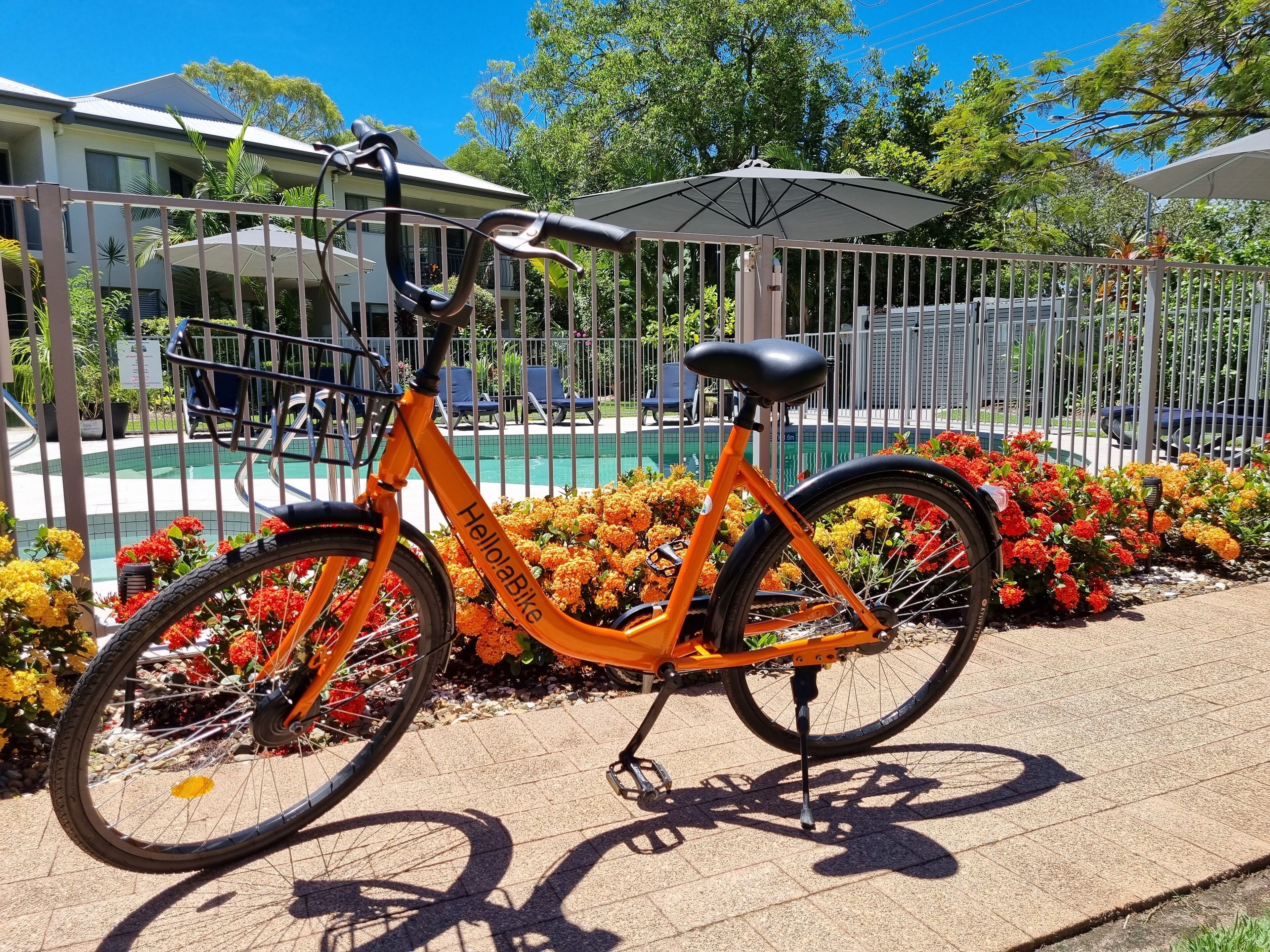 Bicicleta estacionada perto de uma piscina com cerca e área de estar ao ar livre.