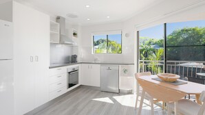 Una cocina moderna con armarios blancos, lavavajillas y un comedor con mesa y sillas.