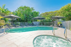 Una piscina al aire libre, sombrillas, sillones reclinables de piscina
