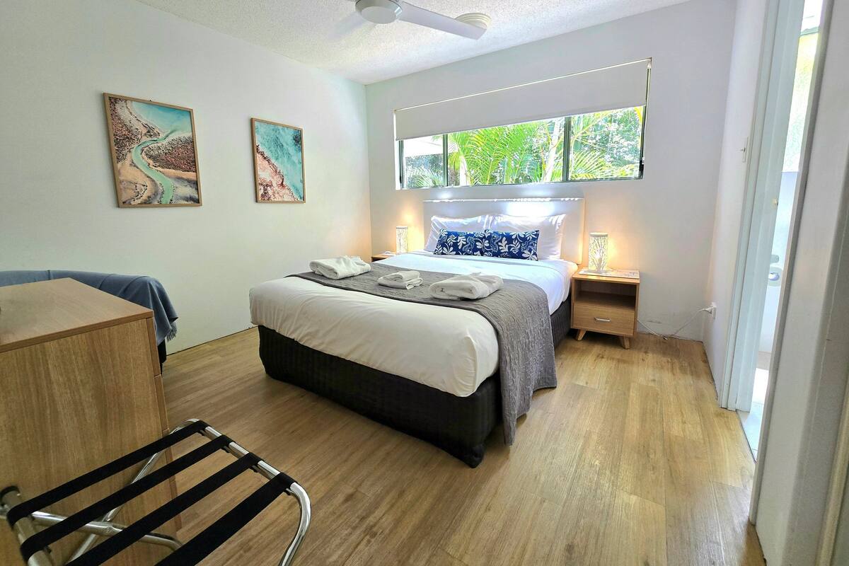 Une chambre à coucher moderne avec un lit, des tables de chevet, un bureau et une chaise.