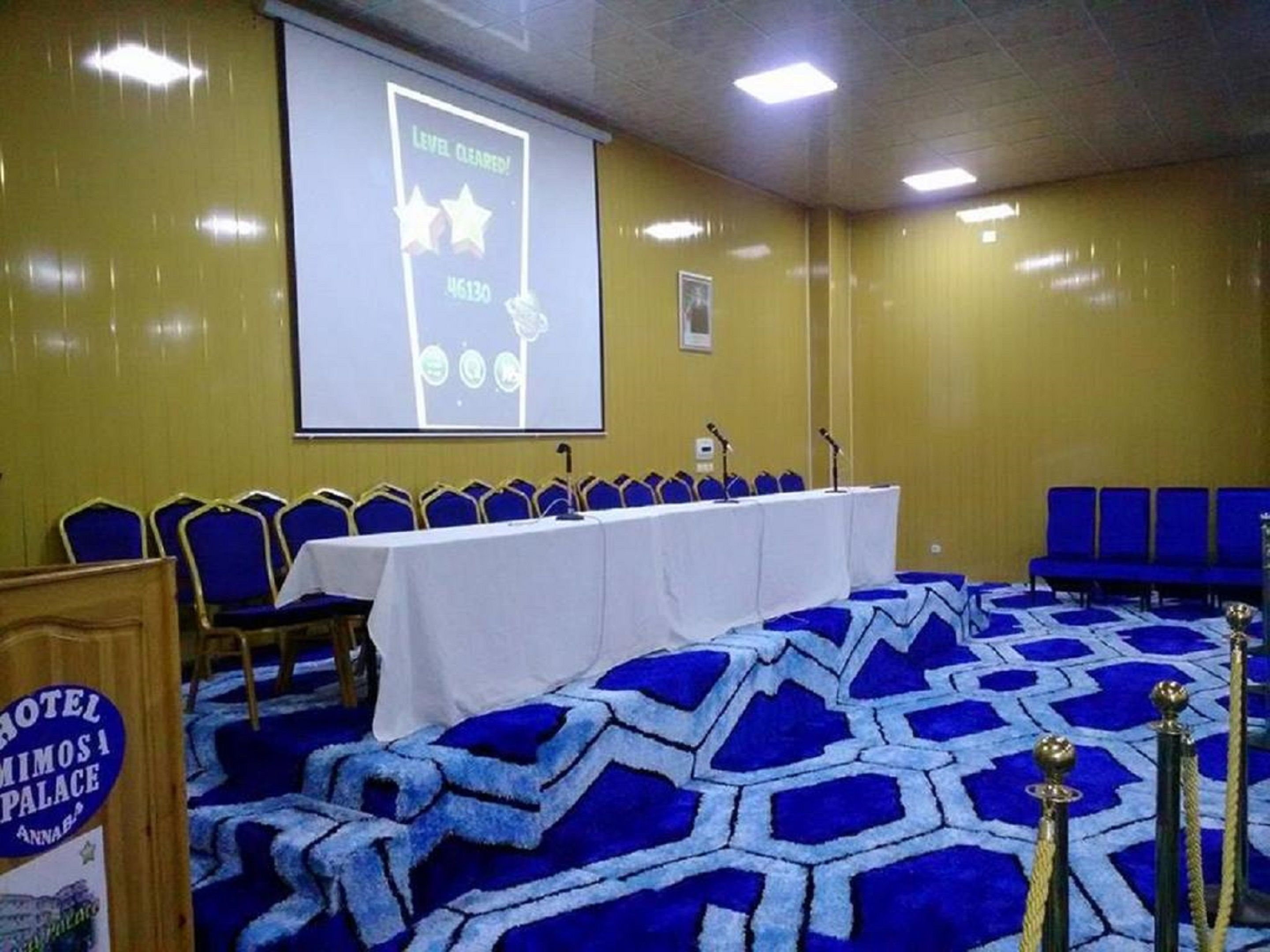A conference room with a long table, blue chairs, and a carpet with a geometric pattern.