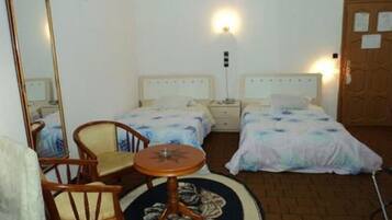 Habitación de hotel con dos camas, una mesa redonda, una silla, un espejo y una puerta con un aviso.