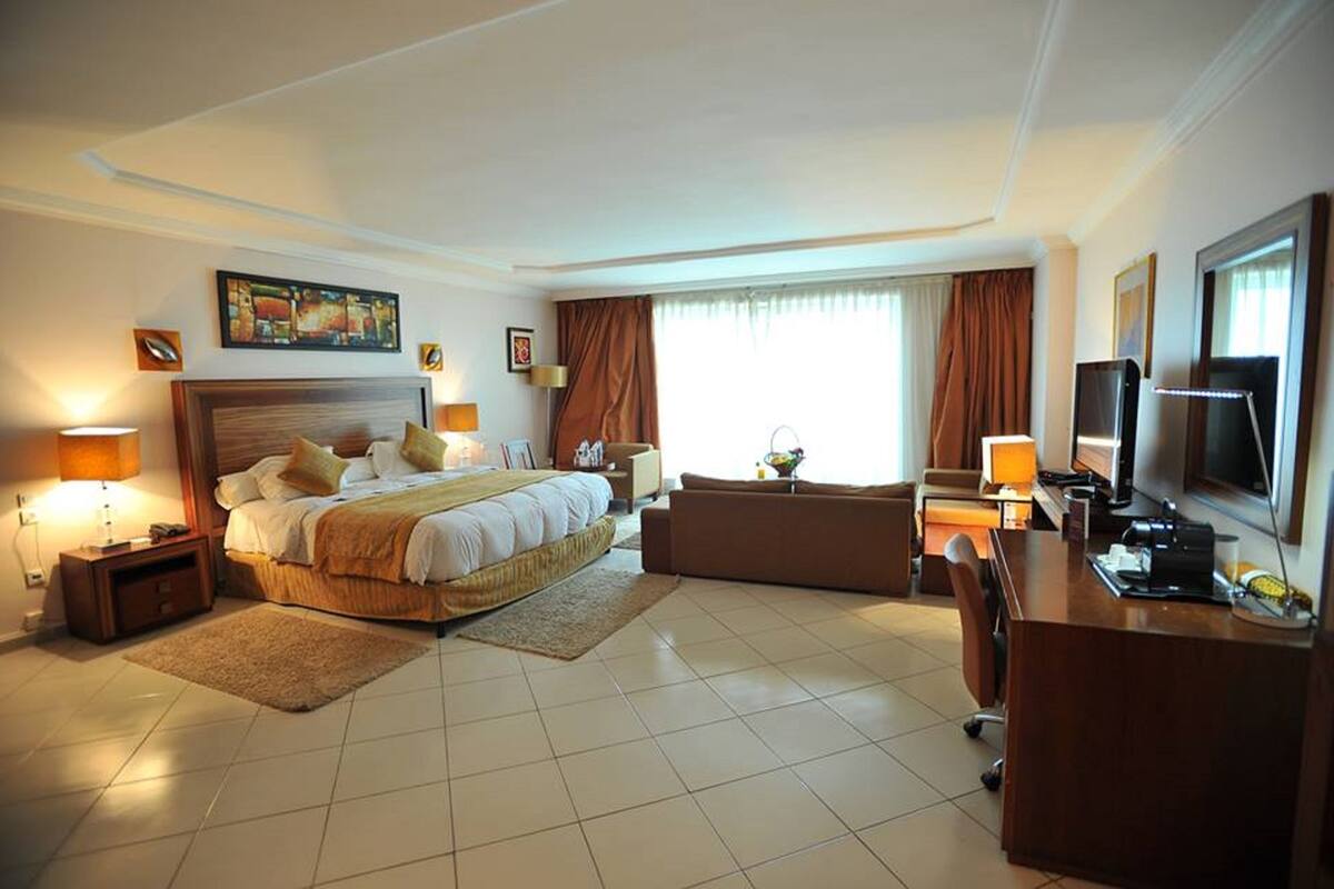 A hotel room with a bed, a desk, a television, and a sofa.