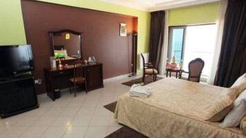 A hotel room with a bed, a desk, a chair, a television, and a window with curtains.