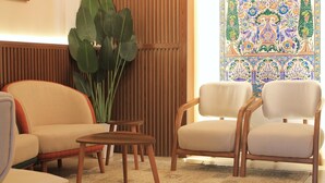 A room with two beige armchairs, a small wooden table, and a large plant. - Palace Appart Hôtel (Algiers)