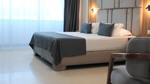 A modern hotel room with a large bed, a headboard with built-in lighting, a chair, and a large window with sheer curtains. - Palace Appart Hôtel (Algiers)