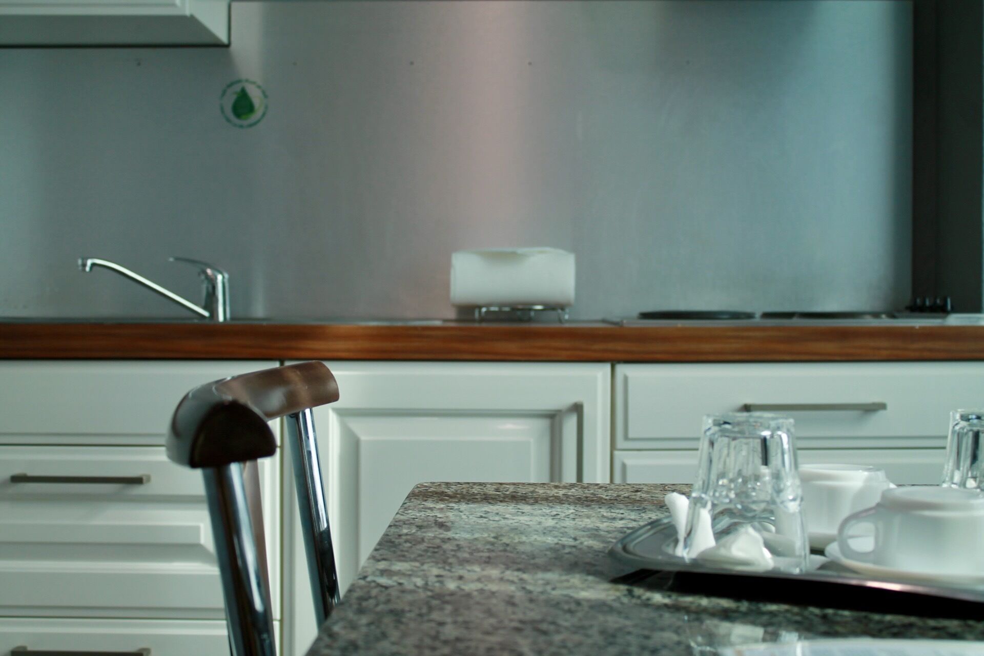A kitchen with white cabinets, a stainless steel range hood, and a wooden countertop.
