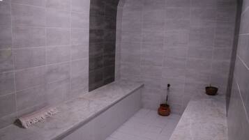 A bathroom with a bathtub, a shower area, and a small sink.