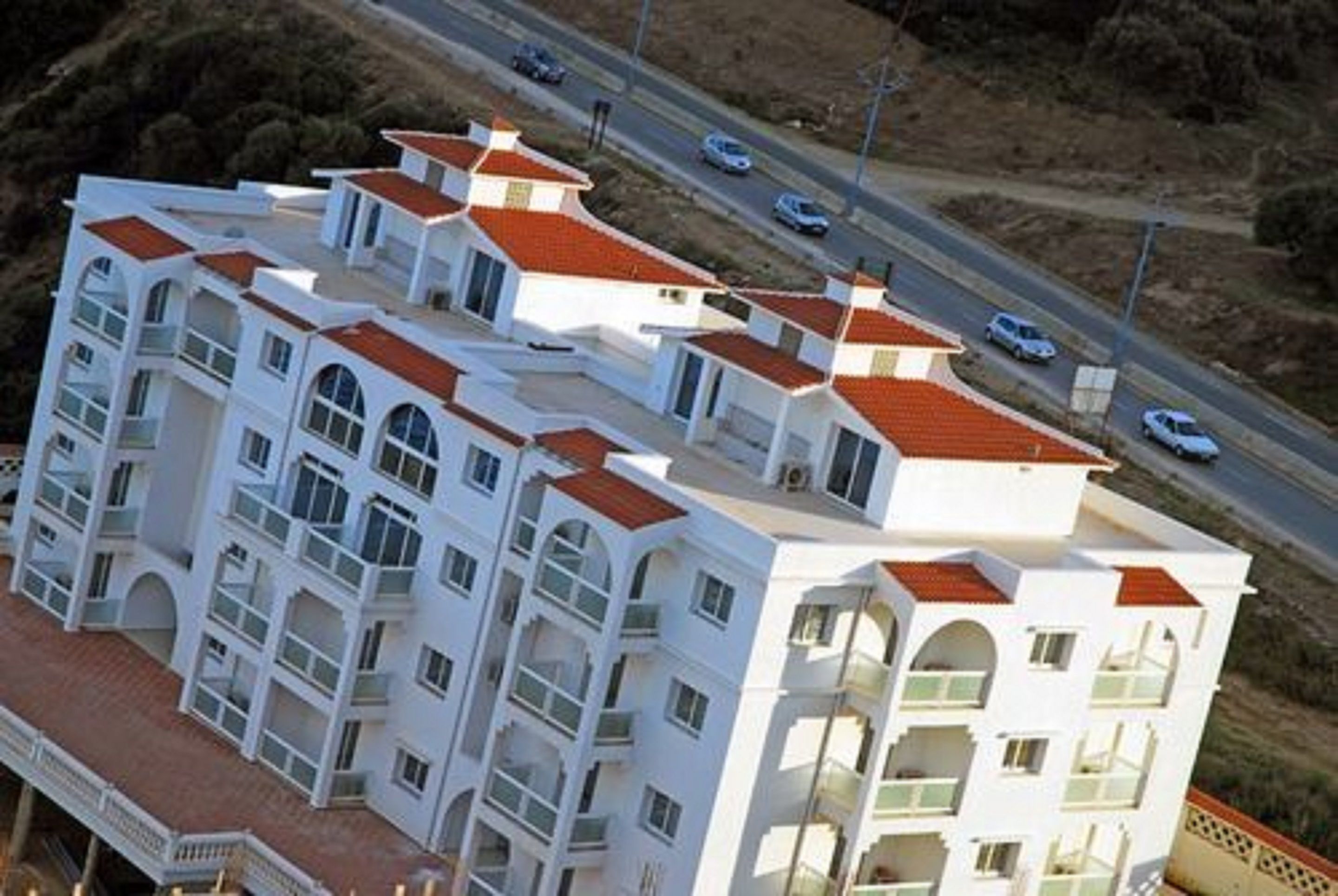 Un hotel de varios pisos con fachada blanca y tejados de tejas rojas.