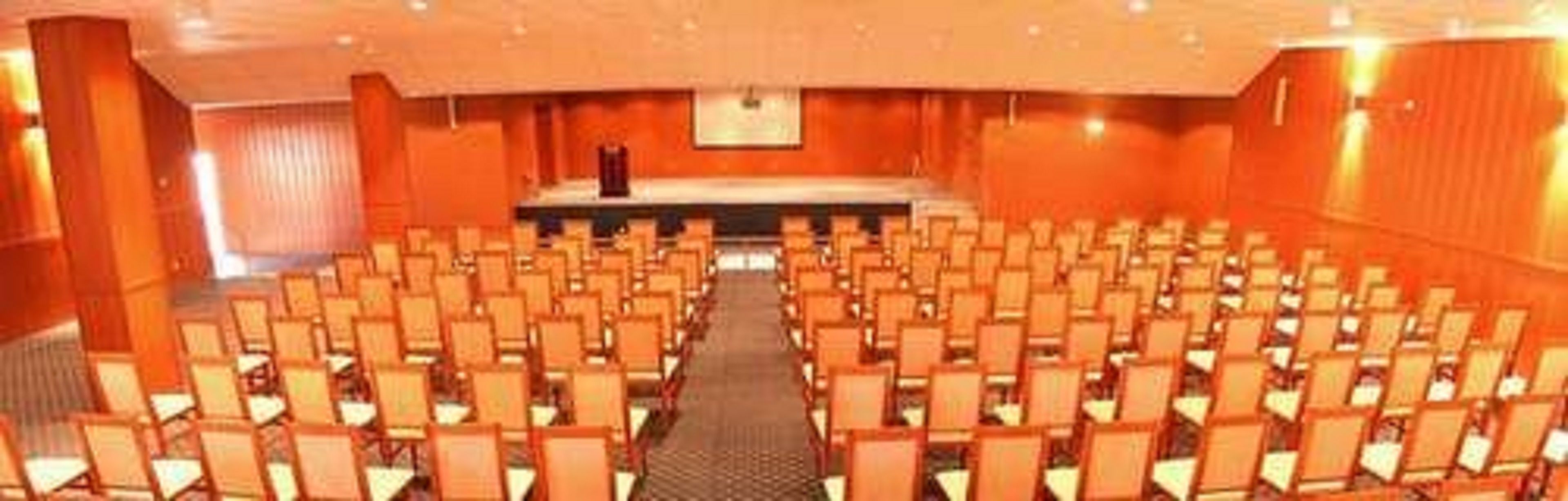 A conference room with rows of chairs facing a stage with a podium.
