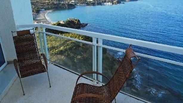 Een balkon met rieten stoelen en uitzicht op de kust.