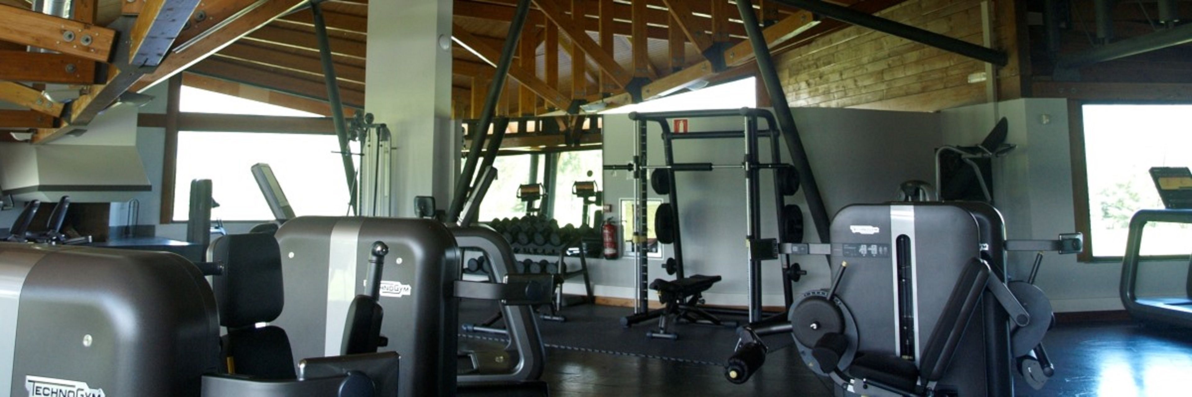 Un gimnasio con diverso equipo de ejercicio, incluyendo máquinas de pesas y mancuernas.