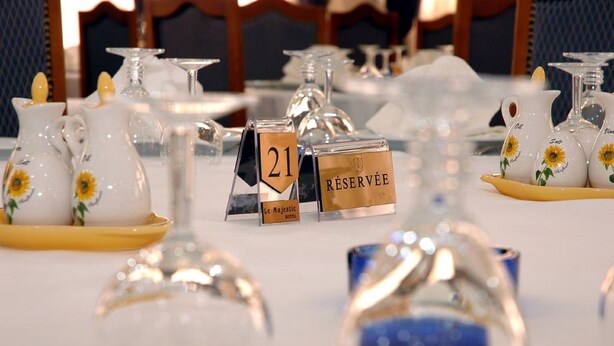 A table set with clear glassware, numbered place cards, and decorative pitchers with sunflowers. - Majestic Annaba (Annaba)