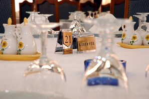 A table set with clear glassware, numbered place cards, and decorative pitchers with sunflowers. - Majestic Annaba (Annaba)