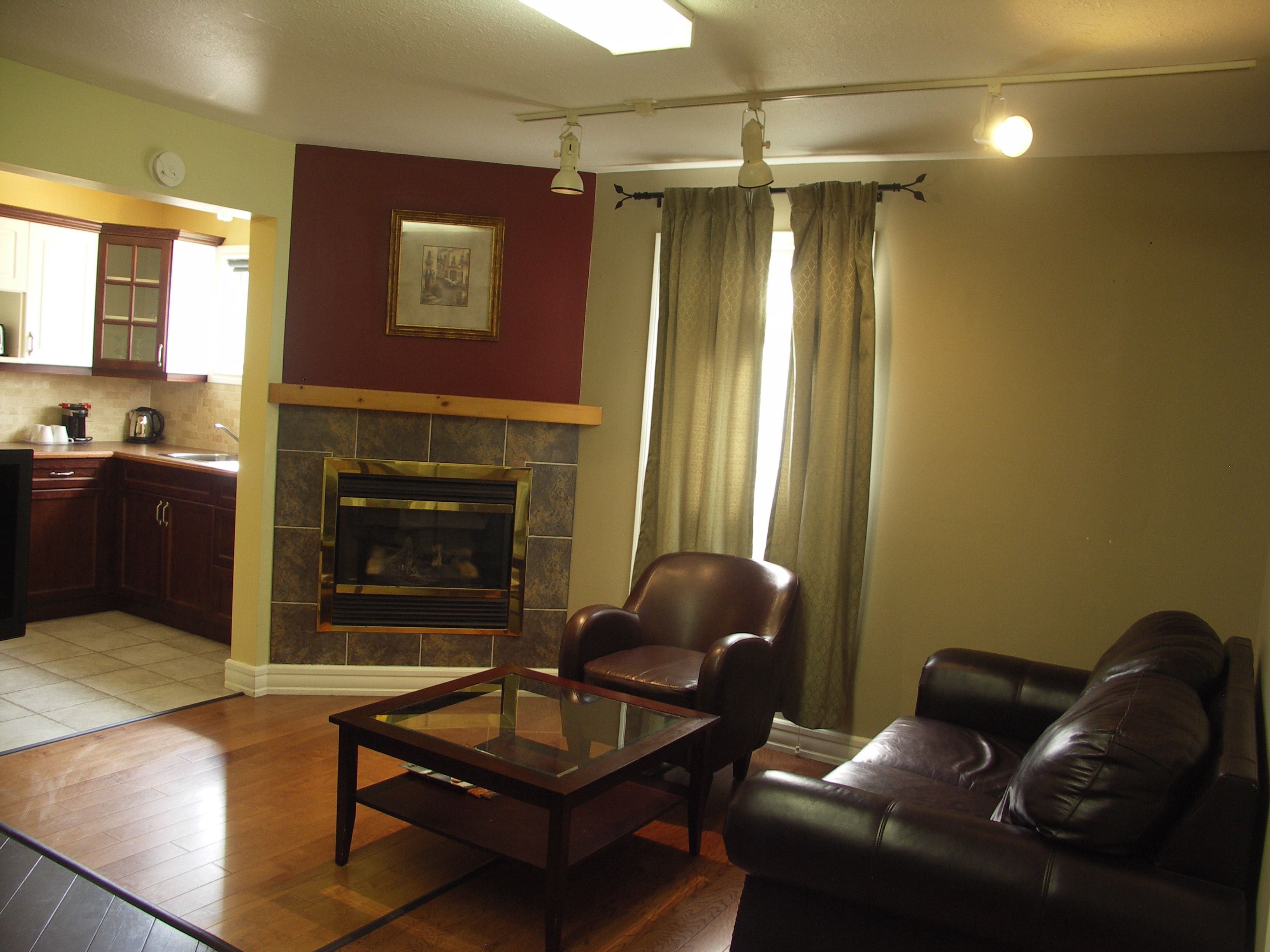 A living room with a fireplace, leather sofa, and a glass coffee table.