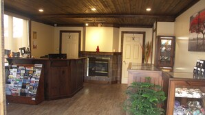 Un intérieur chaleureux avec un comptoir d’accueil en bois, une cheminée et une vitrine où sont exposés des bijoux.
