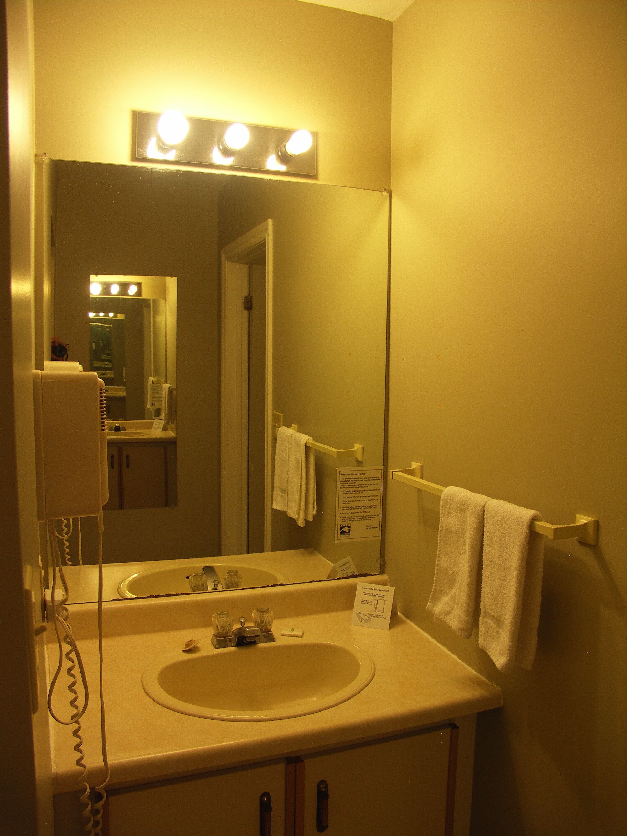 A bathroom with a sink, mirror, and towel rack.