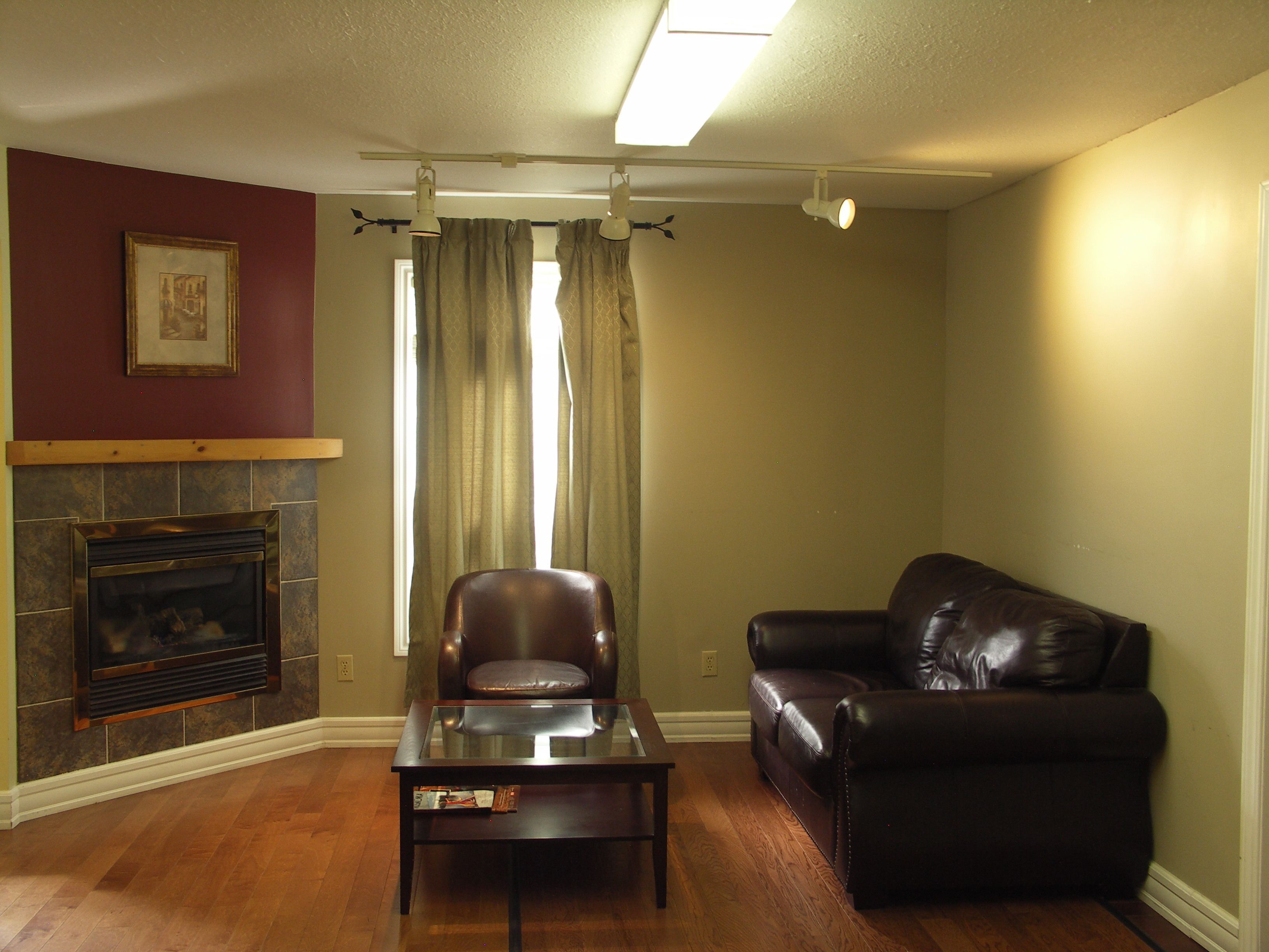 A living room with a fireplace, leather sofa, and a glass coffee table.