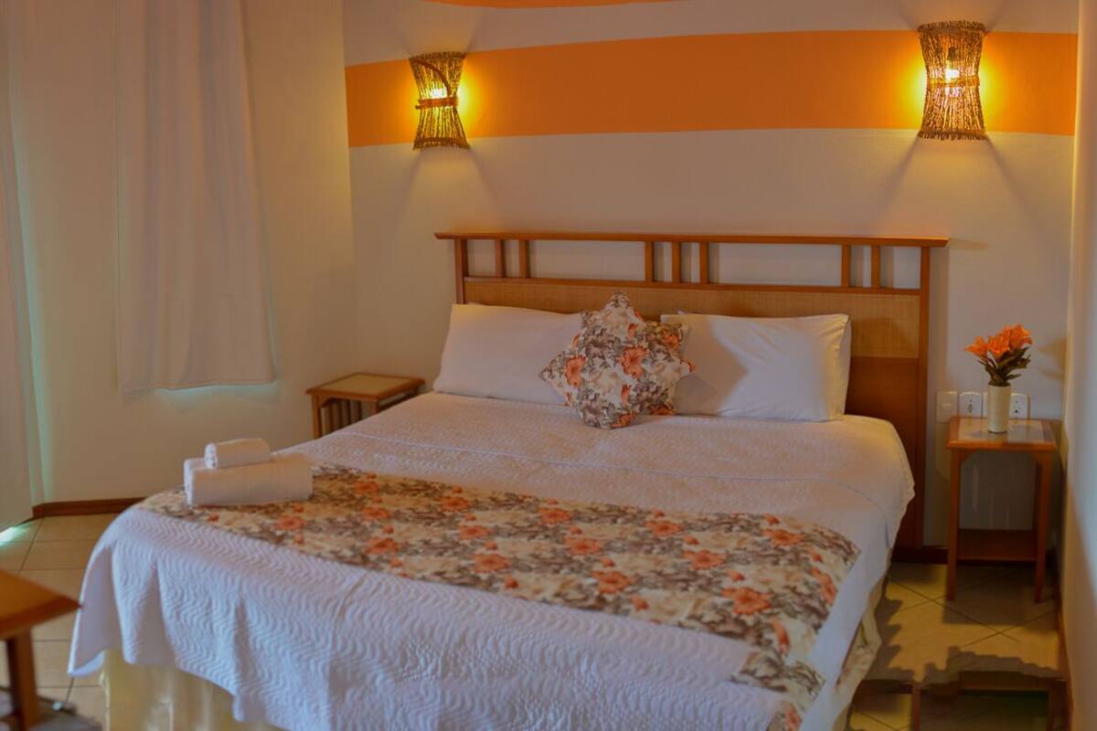 Ein Hotelzimmer mit einem großen Bett, zwei Nachttischen, einem Schreibtisch und einem Stuhl.