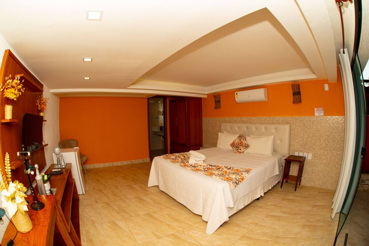 Ein Hotelzimmer mit einem großen Bett, einem Schreibtisch mit Computer und einem durchgegangenen Tür sichtbaren Badezimmer.